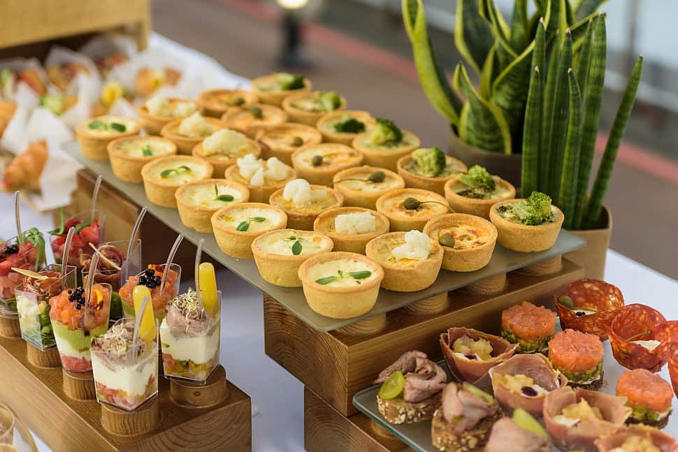 Masă cu platouri de catering Nakupnos: tartelete, verrines și finger food aranjate pentru un eveniment